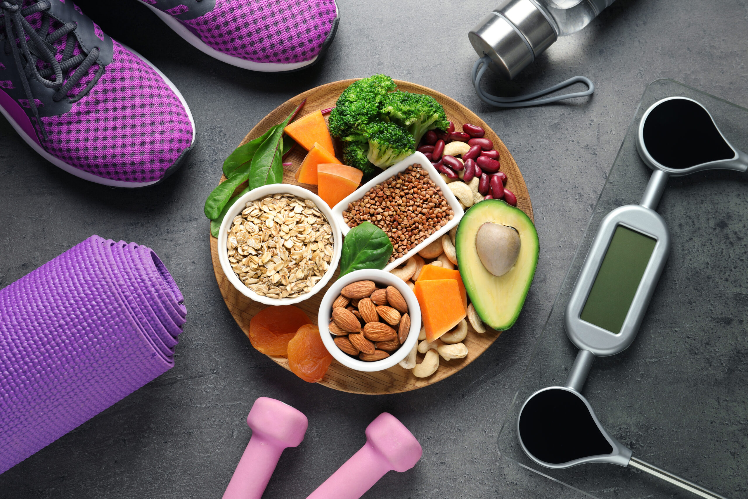 Plate with heart-healthy products and sports equipment on grey background, flat lay